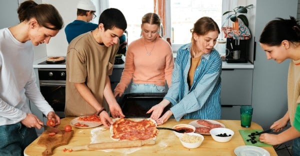 Pizzaworkshop mit 6 Teilnehmern backt gemeinsam eine Pizza