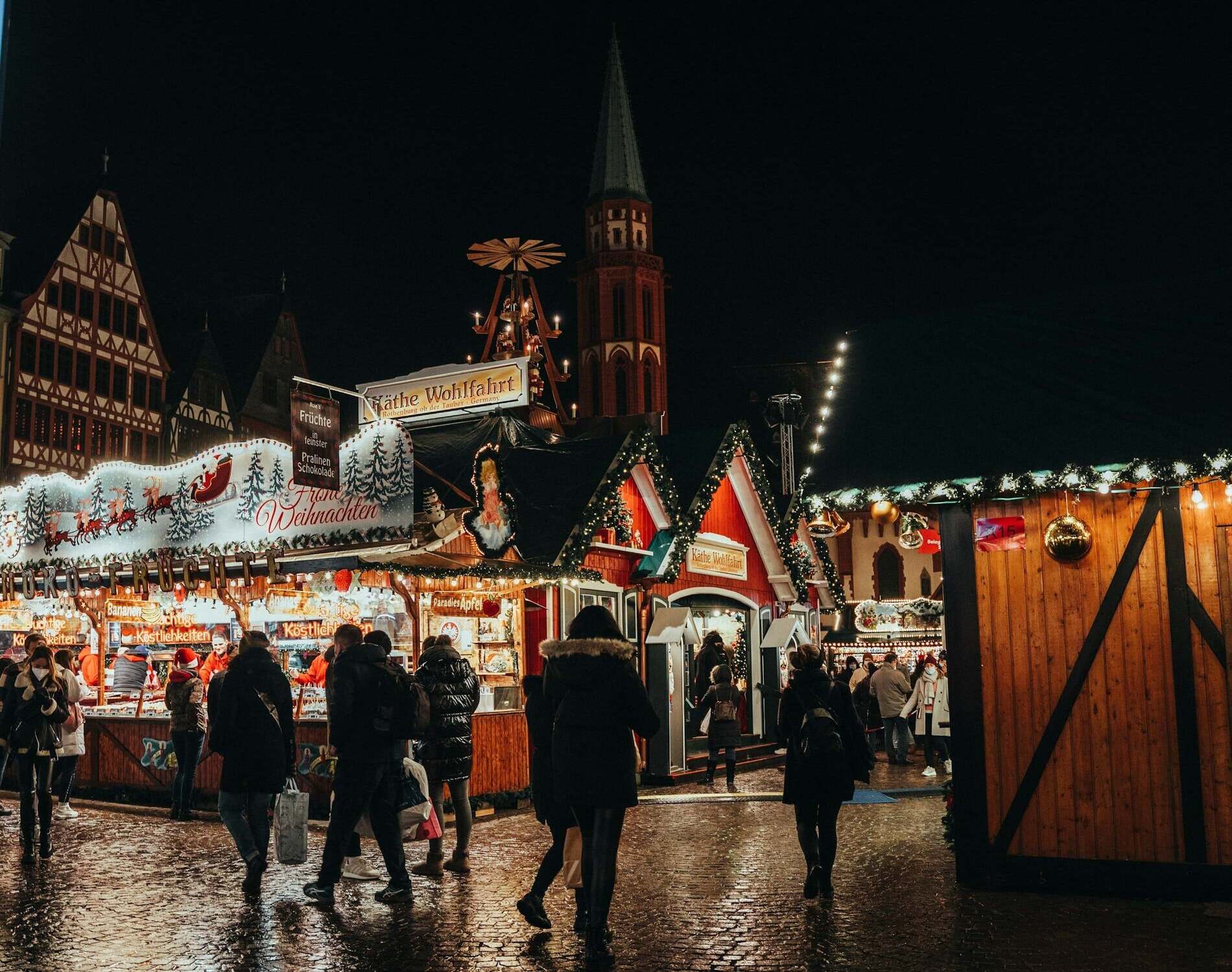 Stimmungsvoller Weihnachtsmarkt bei Nacht mit festlich beleuchteten Buden, traditionellen Fachwerkhäusern und geschmückten Tannen. Besucher schlendern durch die weihnachtlich dekorierten Gassen, genießen Glühwein, gebrannte Mandeln und festliche Atmosphäre – perfektes Ambiente für ein unvergessliches Weihnachtsevent oder Teambuilding in der Adventszeit.