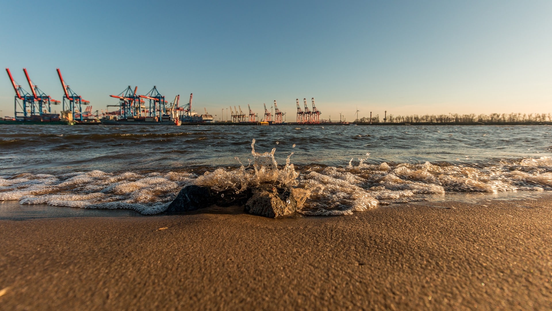 Strandabschnitt an der Elbe mit Blick auf Hafenkräne – maritimes Ambiente für ein Sommerfest in der Hafenstadt Hamburg.